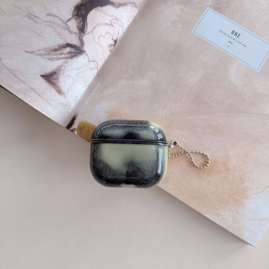 Midnight smoke air pod case with a keychain on a textured surface